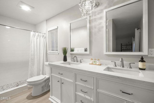 bathroom featuring curtained shower, wood-type flooring, vanity, toilet, and an inviting chandelier