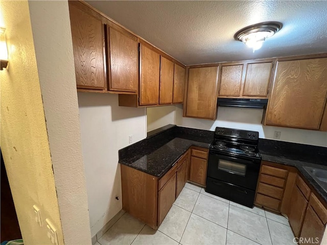 kitchen featuring black electric range oven, light tile patterned floors, a textured ceiling, and dark stone counters