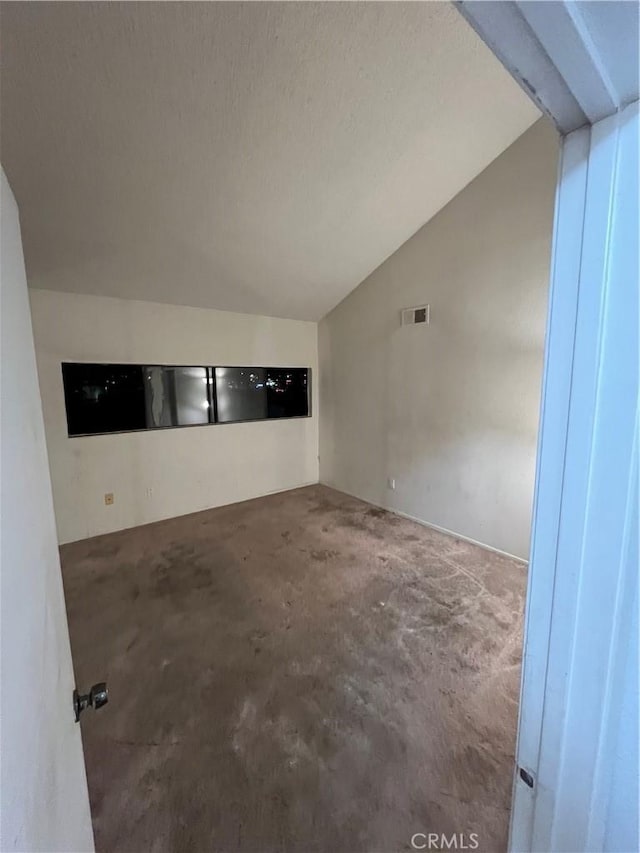 spare room featuring lofted ceiling and concrete floors