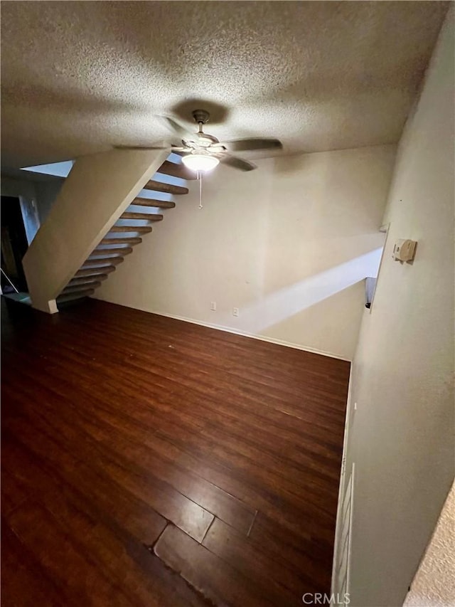 empty room featuring ceiling fan, dark hardwood / wood-style floors, and a textured ceiling