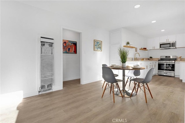 dining space with sink and light wood-type flooring