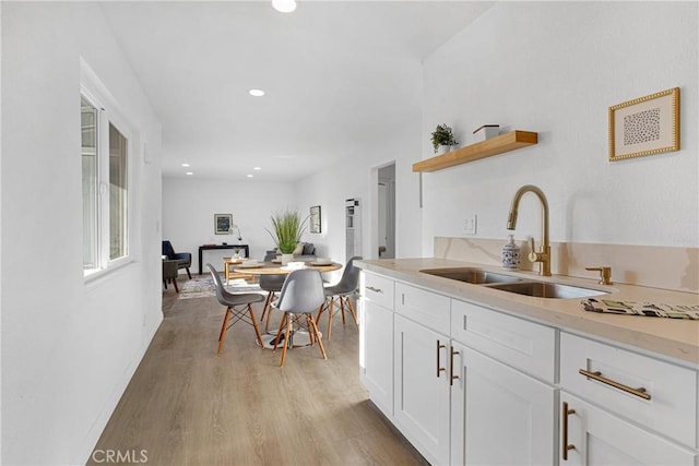 kitchen with white cabinetry, sink, and light hardwood / wood-style flooring