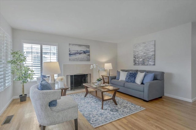 living room with a tile fireplace and light hardwood / wood-style flooring