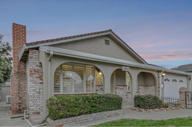 single story home with a garage, central AC unit, and covered porch