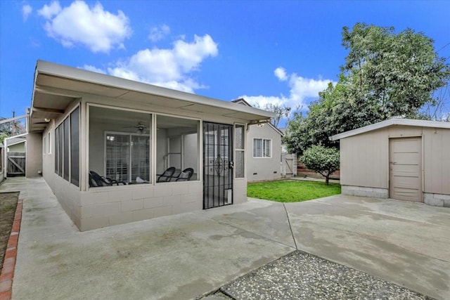 rear view of property with a patio, a sunroom, and a storage shed