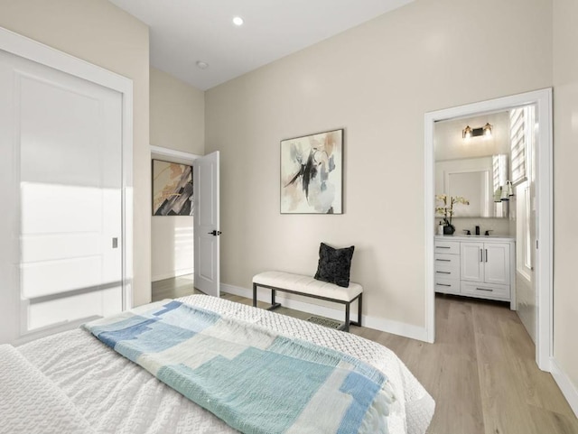 bedroom with connected bathroom, sink, and light wood-type flooring