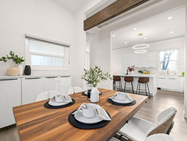 dining room with beam ceiling and light hardwood / wood-style floors