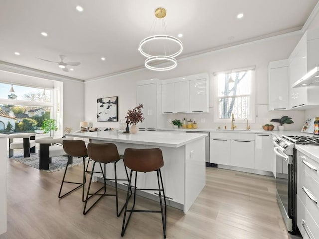 kitchen with sink, white cabinetry, stainless steel appliances, a center island, and decorative light fixtures