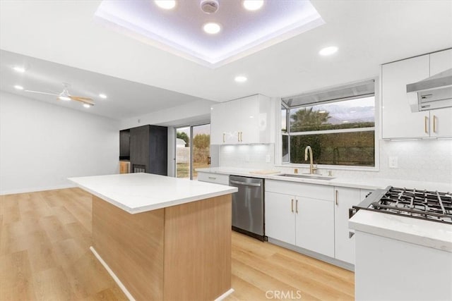 kitchen featuring sink, light hardwood / wood-style flooring, dishwasher, white cabinetry, and a center island