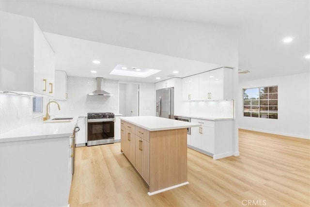 kitchen featuring white cabinetry, stainless steel appliances, a center island, and wall chimney exhaust hood