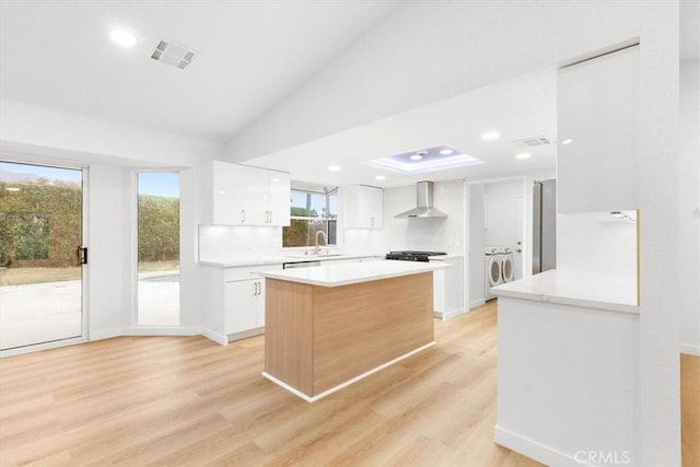 kitchen with wall chimney exhaust hood, light hardwood / wood-style floors, sink, and white cabinets