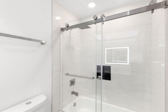 bathroom with toilet and combined bath / shower with glass door