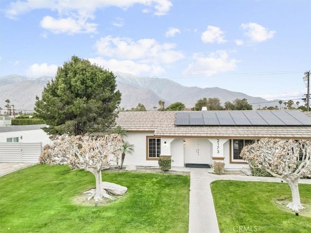 single story home with a mountain view, a front yard, and solar panels