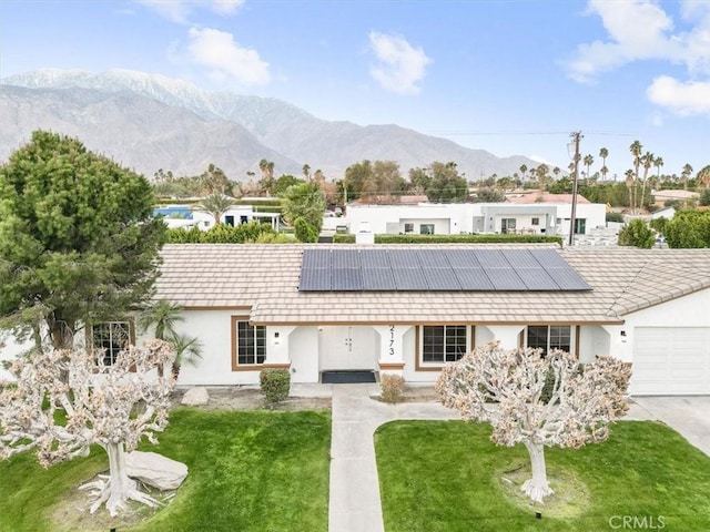 single story home featuring a mountain view, a front yard, and solar panels