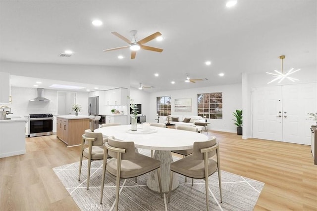 dining space featuring lofted ceiling, sink, and light wood-type flooring