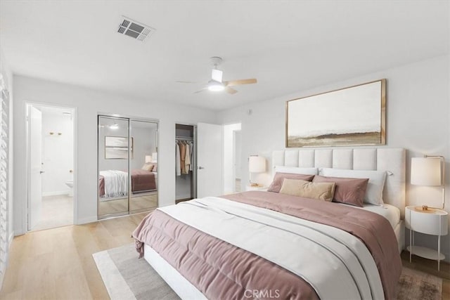 bedroom with ceiling fan, ensuite bath, two closets, and light wood-type flooring