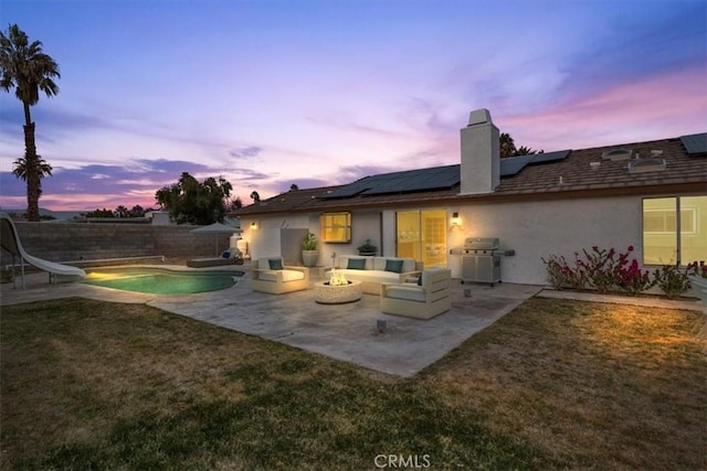 2173 N Viminal Rd, Palm Springs, CA 92262 - back of house at dusk with a patio area, a chimney, solar panels, stucco siding, and an outdoor living space with a fire pit