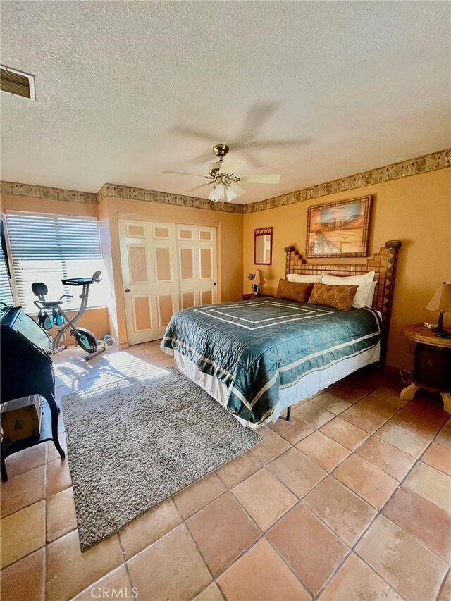 tiled bedroom featuring ceiling fan, a closet, and a textured ceiling