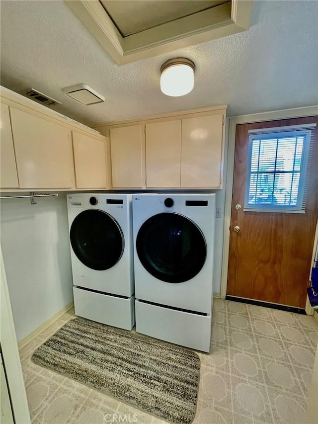 washroom with cabinets, washing machine and dryer, and a textured ceiling