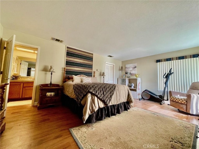 bedroom featuring dark hardwood / wood-style floors, ensuite bath, and a closet