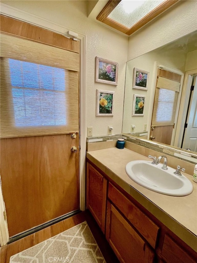 bathroom featuring hardwood / wood-style flooring, vanity, and a skylight