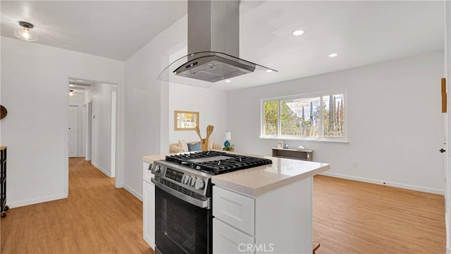 kitchen with light hardwood / wood-style flooring, island range hood, stainless steel range with gas cooktop, and white cabinets