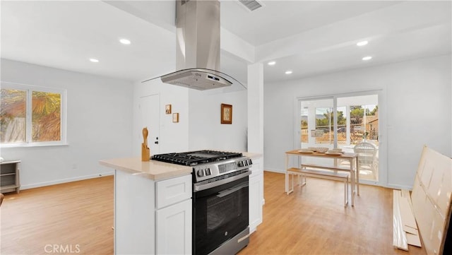 kitchen featuring white cabinets, island range hood, light hardwood / wood-style floors, and stainless steel gas range oven