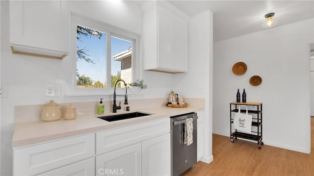 kitchen with sink, stainless steel dishwasher, white cabinets, and light wood-type flooring