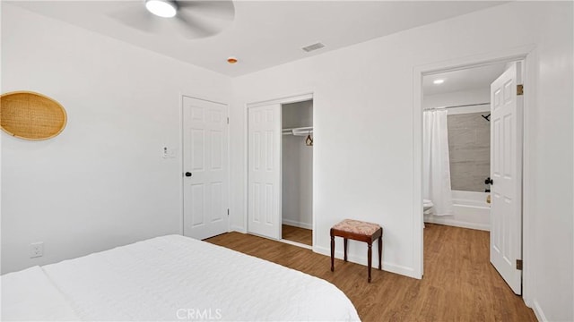 bedroom featuring hardwood / wood-style flooring, ceiling fan, ensuite bathroom, and a closet