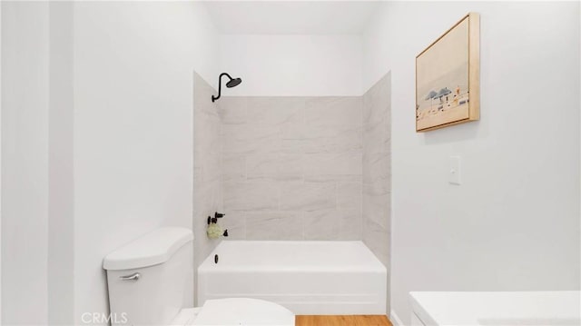 bathroom featuring tiled shower / bath, hardwood / wood-style floors, and toilet