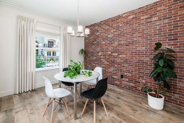 dining area with an inviting chandelier, ornamental molding, brick wall, and light hardwood / wood-style floors