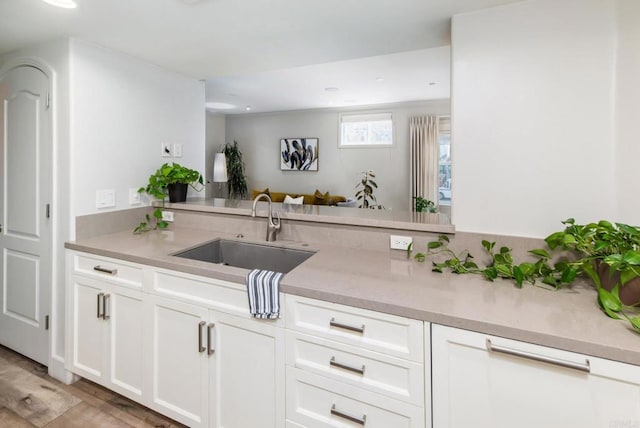 bar featuring white cabinetry, light hardwood / wood-style floors, and sink