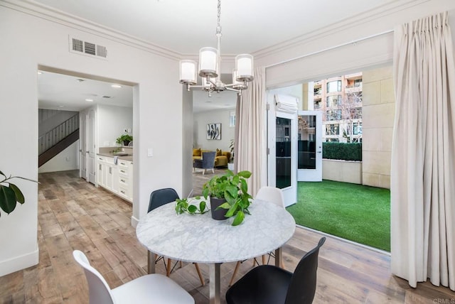 dining space featuring crown molding, light hardwood / wood-style flooring, and a chandelier