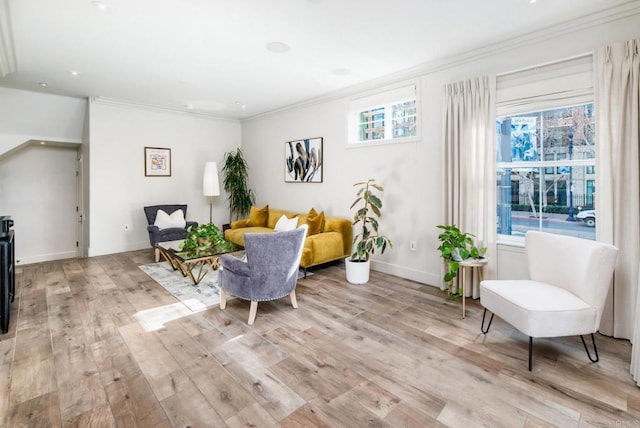 living area with ornamental molding, light wood-type flooring, and a wealth of natural light