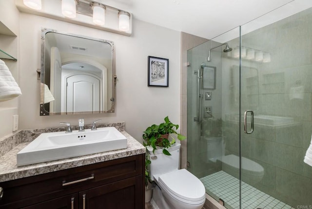 bathroom with vanity, toilet, and a shower with shower door