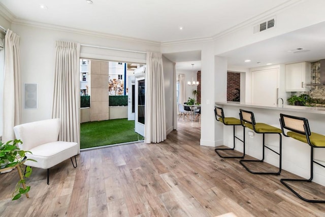 interior space featuring white cabinetry, backsplash, a notable chandelier, crown molding, and light wood-type flooring