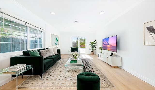 living room with ornamental molding and light hardwood / wood-style floors