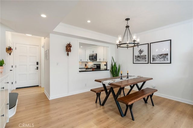 dining space with ornamental molding, a chandelier, and light hardwood / wood-style floors