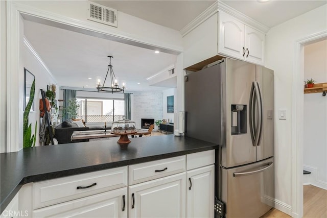 kitchen featuring stainless steel fridge, an inviting chandelier, a fireplace, light hardwood / wood-style floors, and white cabinets