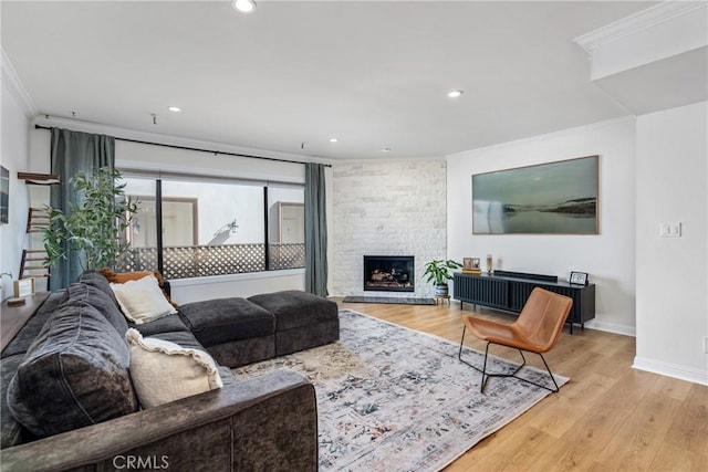 living room featuring crown molding, a fireplace, and light wood-type flooring