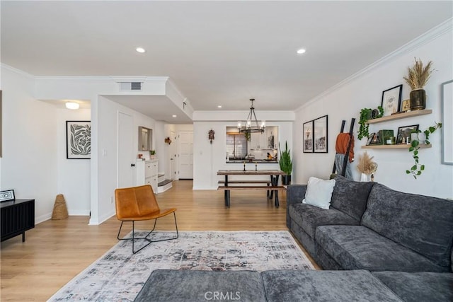 living room with a notable chandelier, light hardwood / wood-style flooring, and ornamental molding