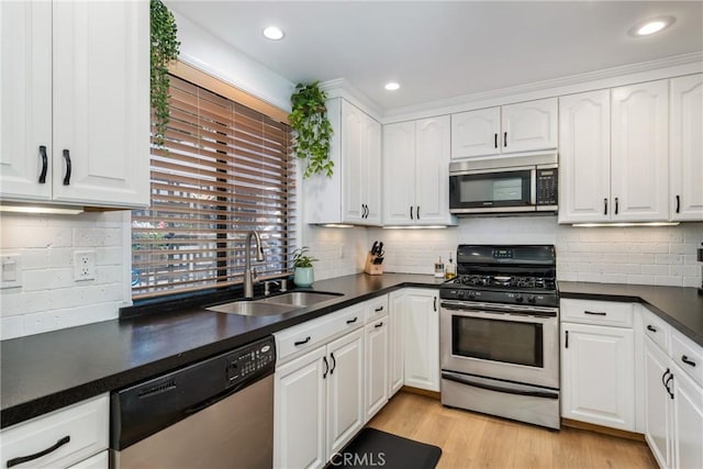 kitchen with sink, light wood-type flooring, appliances with stainless steel finishes, white cabinets, and backsplash