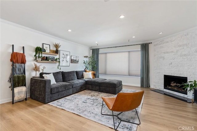 living room featuring crown molding, a stone fireplace, and light hardwood / wood-style floors