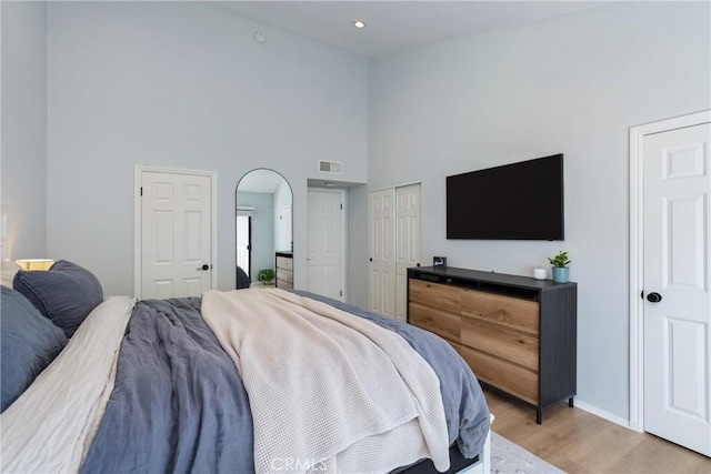 bedroom with a towering ceiling and light hardwood / wood-style floors