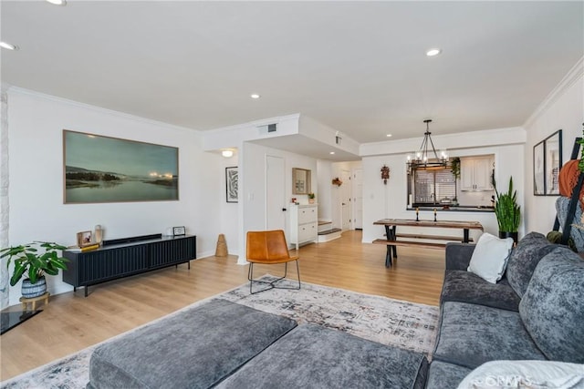 living room featuring crown molding, an inviting chandelier, and hardwood / wood-style floors