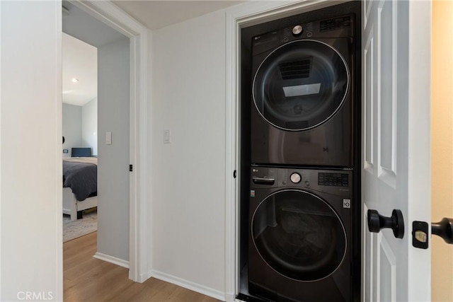 laundry room with stacked washer / dryer and light wood-type flooring