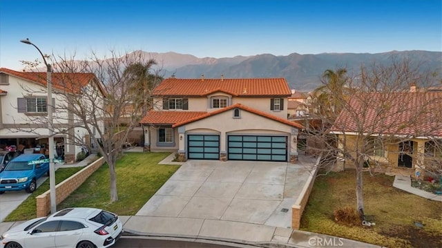 view of front of home featuring a mountain view, a garage, and a front lawn