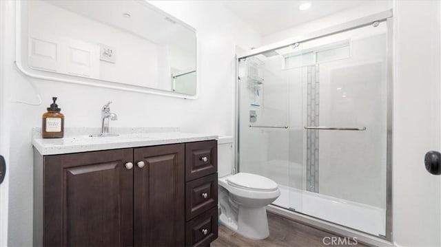 bathroom featuring hardwood / wood-style floors, vanity, toilet, and a shower with shower door