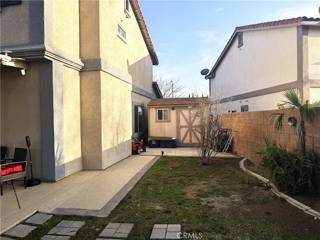 view of yard featuring an outbuilding, a storage shed, a patio area, and fence