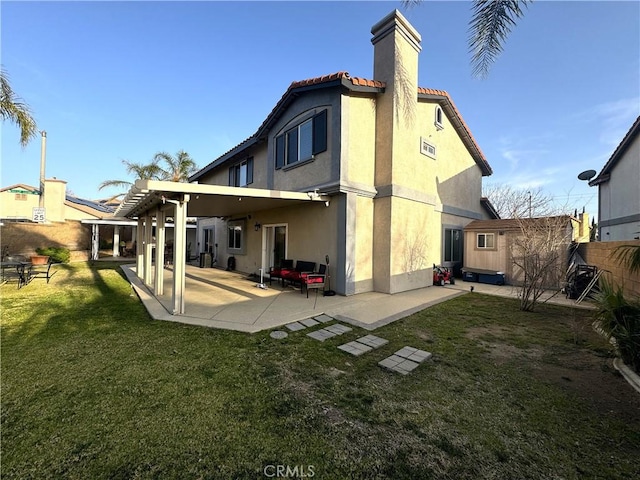 back of house with a lawn, a patio, a chimney, a tiled roof, and stucco siding